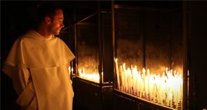 Frate osserva candele accese a Lourdes