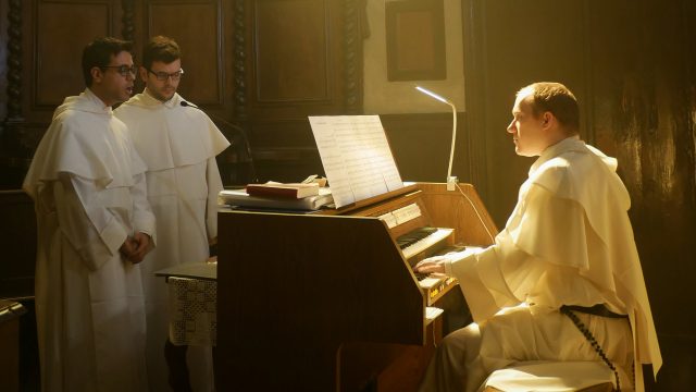 Un frate domenicano suona l'Organo, mentre due altri due frati cantano