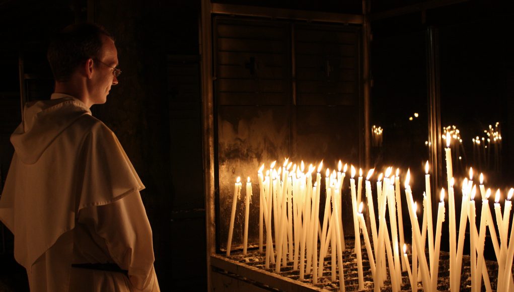 Frate prega davanti a ceri a Lourdes