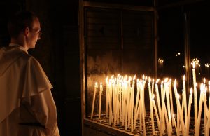 Frate prega davanti a ceri a Lourdes