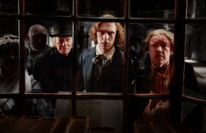 Tre uomini si affacciano verso l'interno di una finestra. Dal film "Dickens, l'uomo che inventò il Natale"