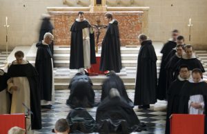 Frati domenicani prostrati davanti al Crocefisso