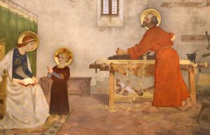 Gesù bambino guarda sua mamma mentre san Giuseppe lavora